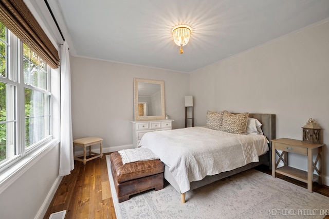 bedroom with dark wood-type flooring and crown molding