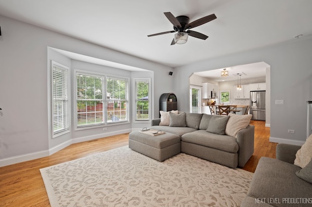 living room featuring light wood-type flooring, ceiling fan, and a healthy amount of sunlight