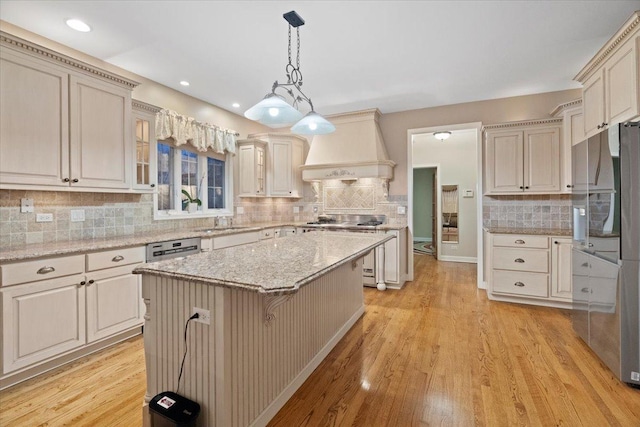 kitchen with a kitchen bar, custom range hood, light hardwood / wood-style flooring, a center island, and hanging light fixtures