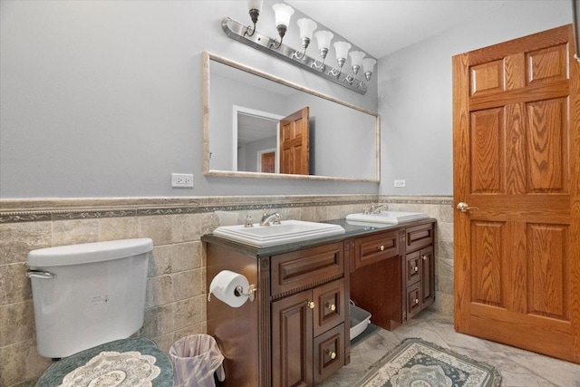 bathroom featuring vanity, toilet, and tile walls