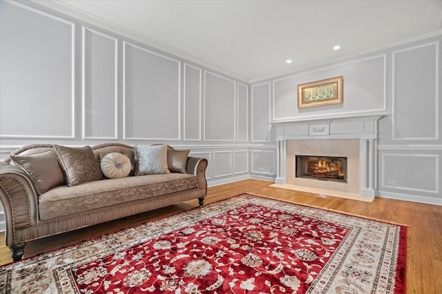 living room featuring hardwood / wood-style flooring, ornamental molding, and a fireplace