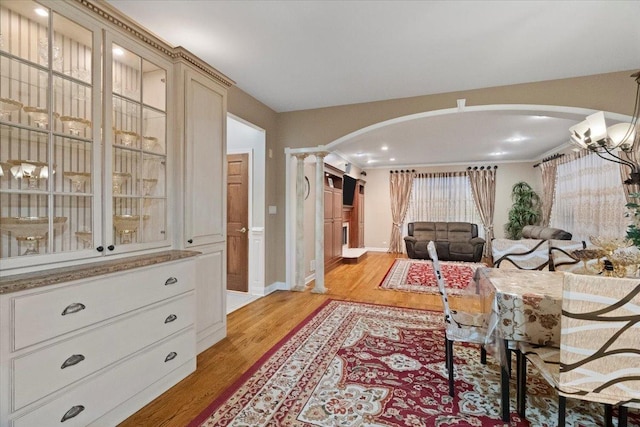 sitting room with light wood-type flooring, decorative columns, and crown molding