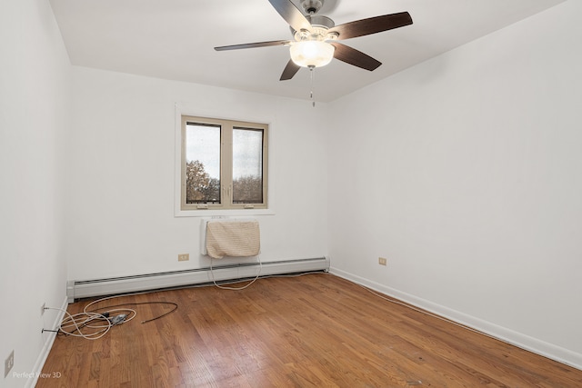 spare room with wood-type flooring, ceiling fan, and a baseboard heating unit