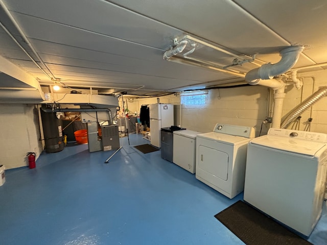 basement with separate washer and dryer, water heater, fridge, and white refrigerator