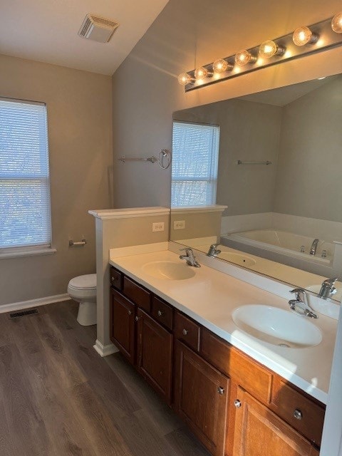 bathroom featuring a bathtub, a wealth of natural light, hardwood / wood-style flooring, and toilet