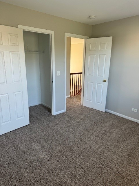 unfurnished bedroom with a closet and dark carpet