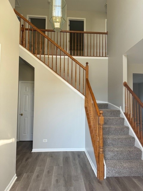 staircase with hardwood / wood-style flooring and a high ceiling