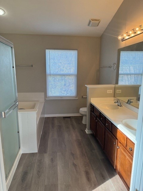 full bathroom featuring wood-type flooring, a healthy amount of sunlight, toilet, and vanity