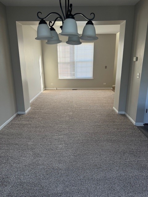 unfurnished room with carpet flooring and an inviting chandelier