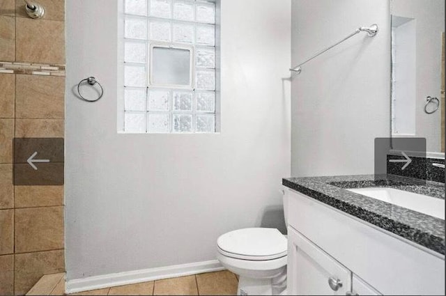 bathroom with tile patterned floors, vanity, tiled shower, and toilet