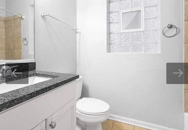 bathroom with toilet, vanity, and tile patterned floors