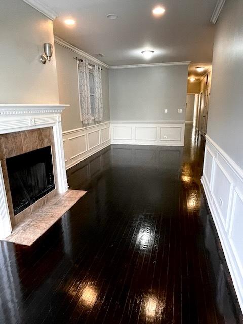 living room with dark hardwood / wood-style floors, ornamental molding, and a fireplace