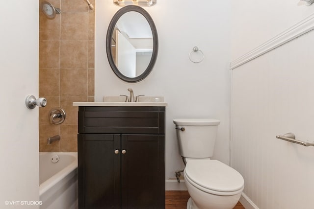 full bathroom featuring vanity, wood-type flooring, tiled shower / bath combo, and toilet