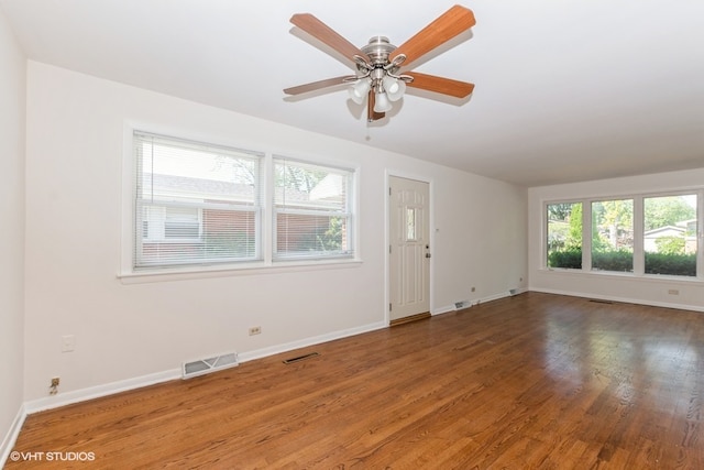 empty room with ceiling fan, a healthy amount of sunlight, and hardwood / wood-style flooring