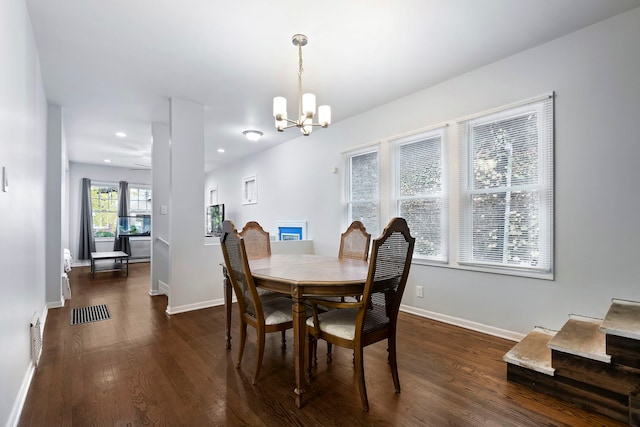 dining room with ceiling fan with notable chandelier and dark hardwood / wood-style floors