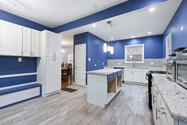 kitchen with white cabinets, light hardwood / wood-style flooring, a kitchen island, and black range