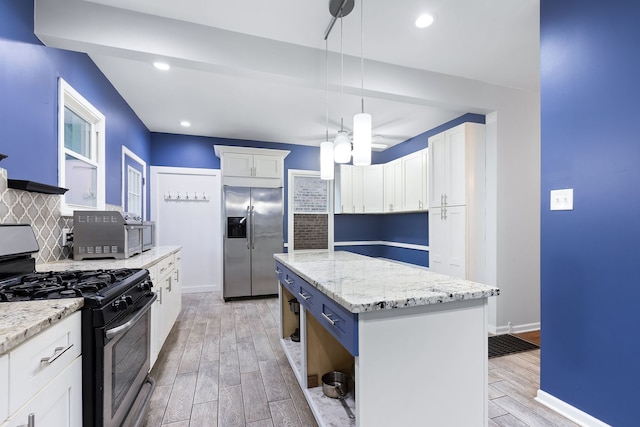 kitchen featuring white cabinets, a kitchen island, decorative light fixtures, and appliances with stainless steel finishes