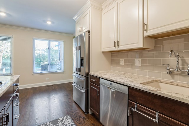 kitchen with stainless steel appliances, white cabinetry, a sink, and crown molding