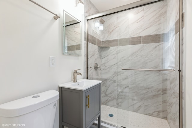 bathroom with vanity, toilet, and a shower with door