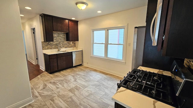 kitchen with dark brown cabinetry, stainless steel appliances, tasteful backsplash, and sink