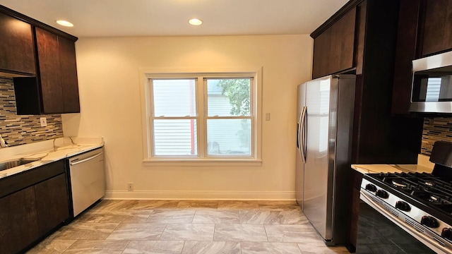 kitchen featuring tasteful backsplash, dark brown cabinetry, light stone counters, and stainless steel appliances