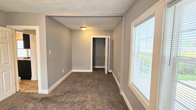 hall with dark colored carpet and a textured ceiling