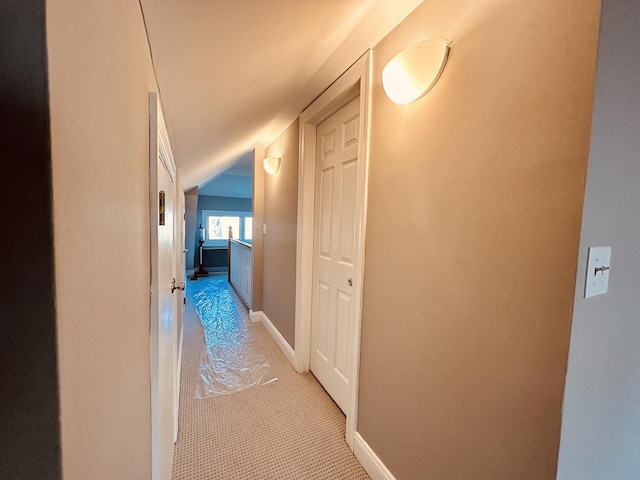 hallway with light colored carpet and lofted ceiling