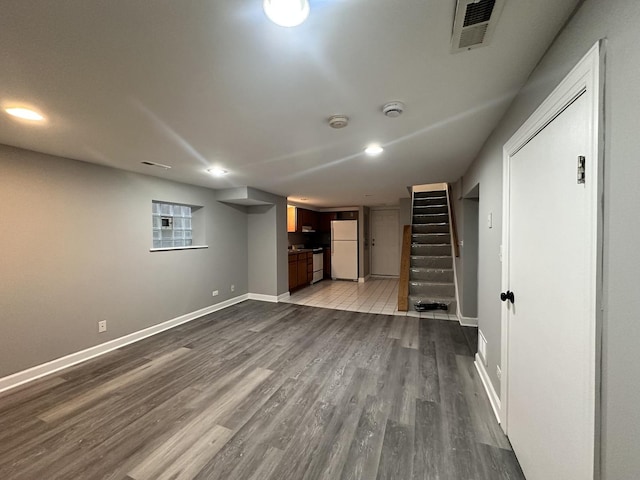 basement featuring wood-type flooring and white refrigerator