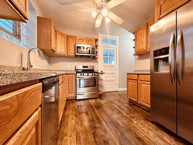 kitchen featuring light stone counters, stainless steel appliances, ceiling fan, dark wood-type flooring, and sink