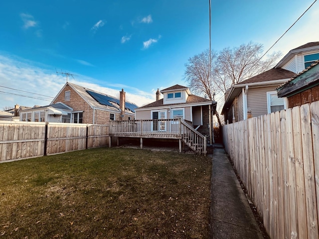 rear view of house featuring a lawn and a deck