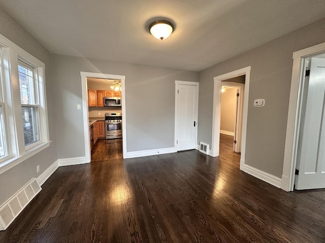 unfurnished living room with dark hardwood / wood-style floors and ceiling fan