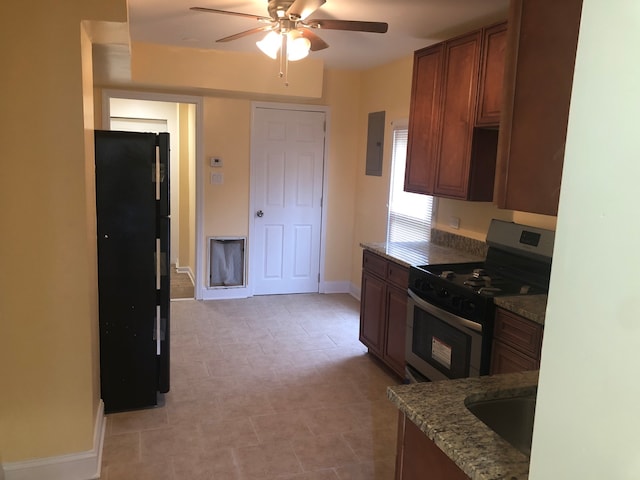 kitchen featuring ceiling fan, stainless steel range, black fridge, electric panel, and stone countertops