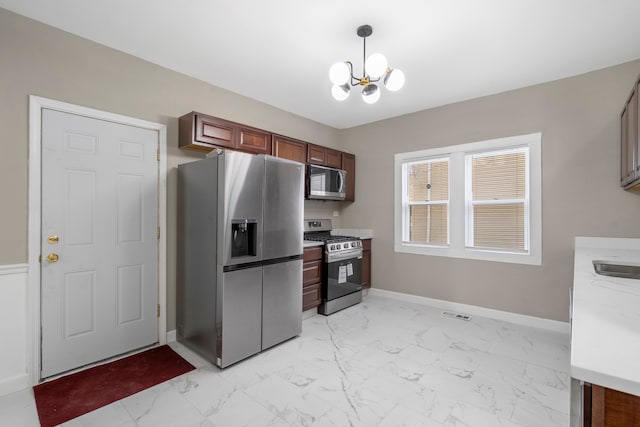 kitchen featuring hanging light fixtures, appliances with stainless steel finishes, light stone counters, and a notable chandelier