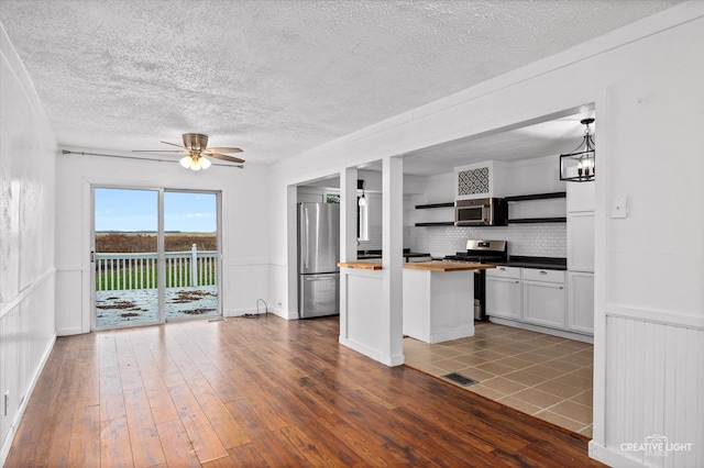 kitchen with butcher block countertops, tasteful backsplash, dark hardwood / wood-style floors, and appliances with stainless steel finishes