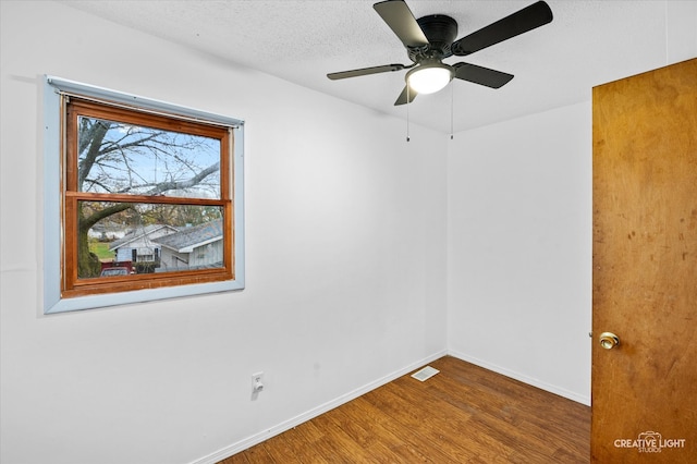 empty room with ceiling fan, a textured ceiling, and hardwood / wood-style flooring