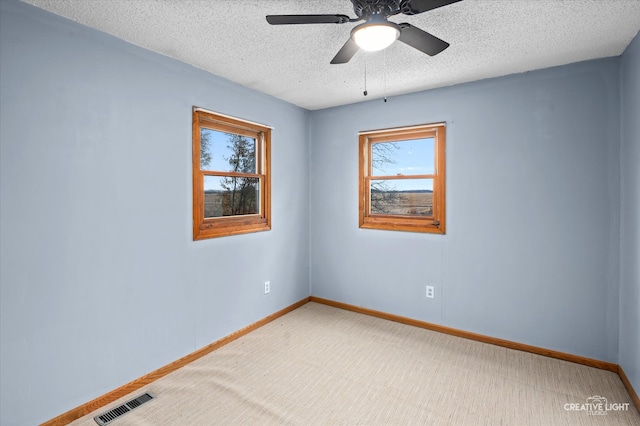 unfurnished room featuring ceiling fan, light colored carpet, and a textured ceiling