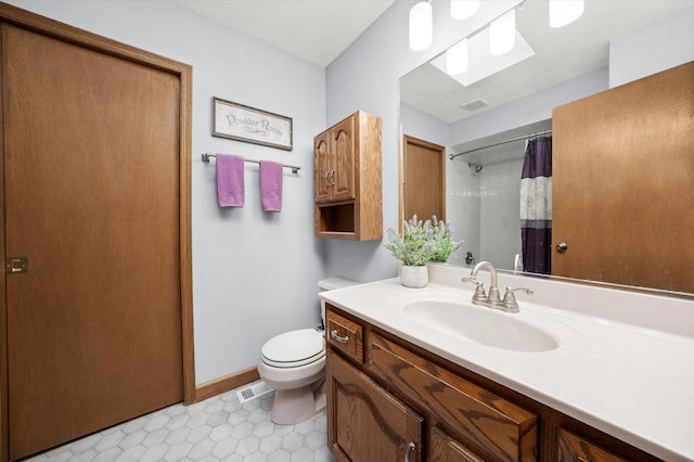 bathroom featuring a skylight, tile patterned floors, walk in shower, vanity, and toilet