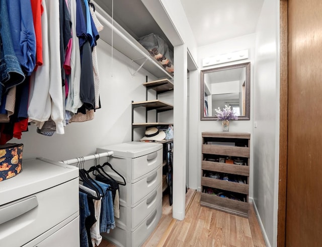 walk in closet with light hardwood / wood-style floors