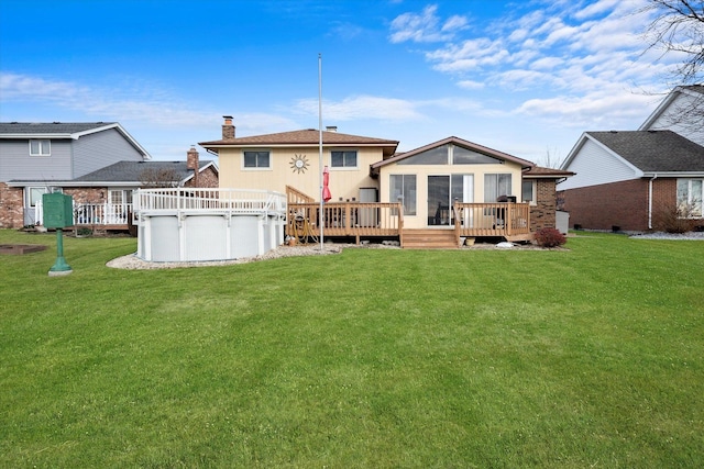 rear view of house featuring a sunroom, a swimming pool side deck, and a yard