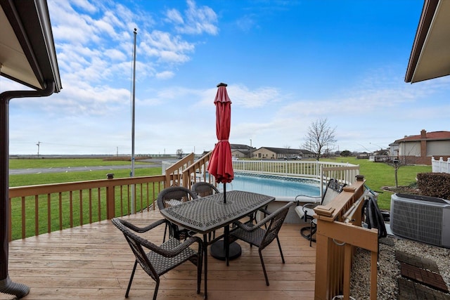 wooden terrace with central air condition unit, a fenced in pool, and a lawn