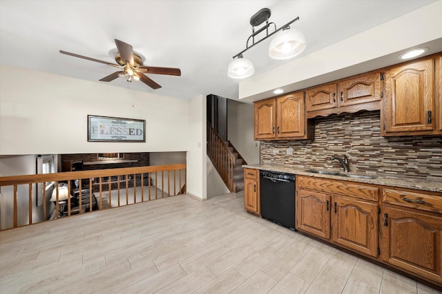 kitchen with light stone countertops, sink, light hardwood / wood-style flooring, dishwasher, and hanging light fixtures