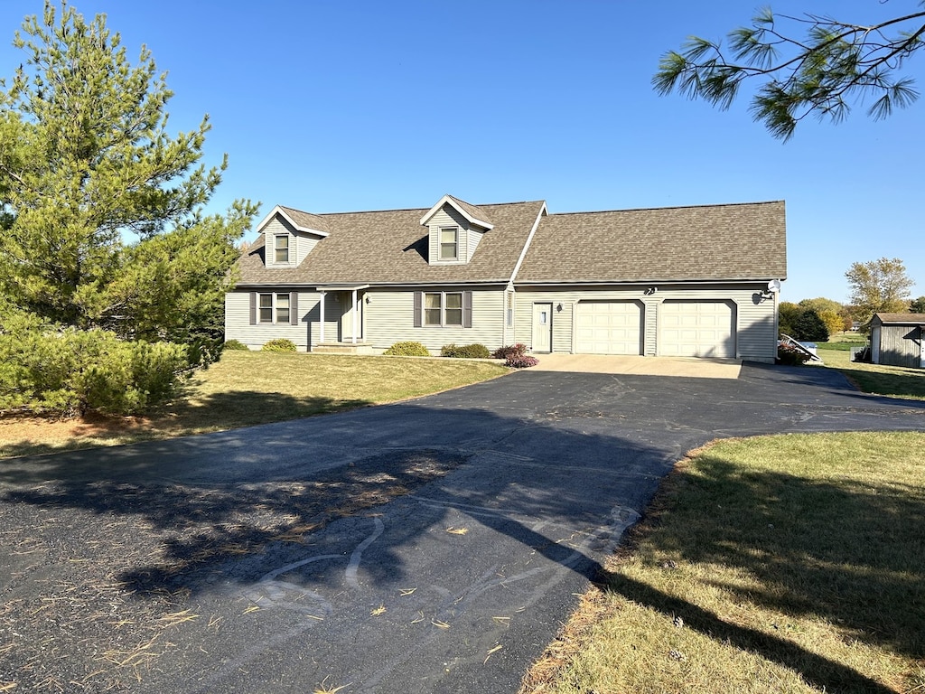 cape cod-style house with a garage and a front lawn