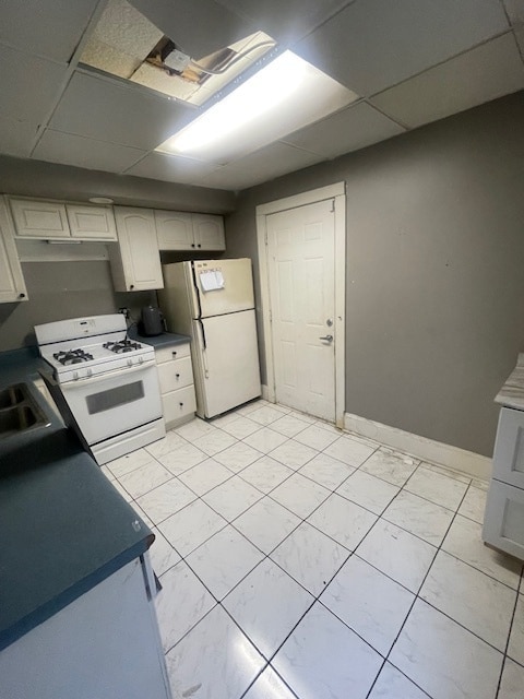 kitchen featuring a drop ceiling, light tile patterned flooring, and white appliances