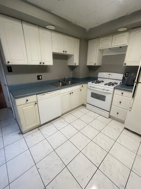 kitchen featuring white appliances, sink, and a paneled ceiling