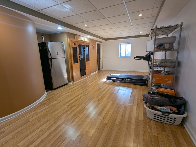 exercise room featuring a paneled ceiling and light hardwood / wood-style flooring