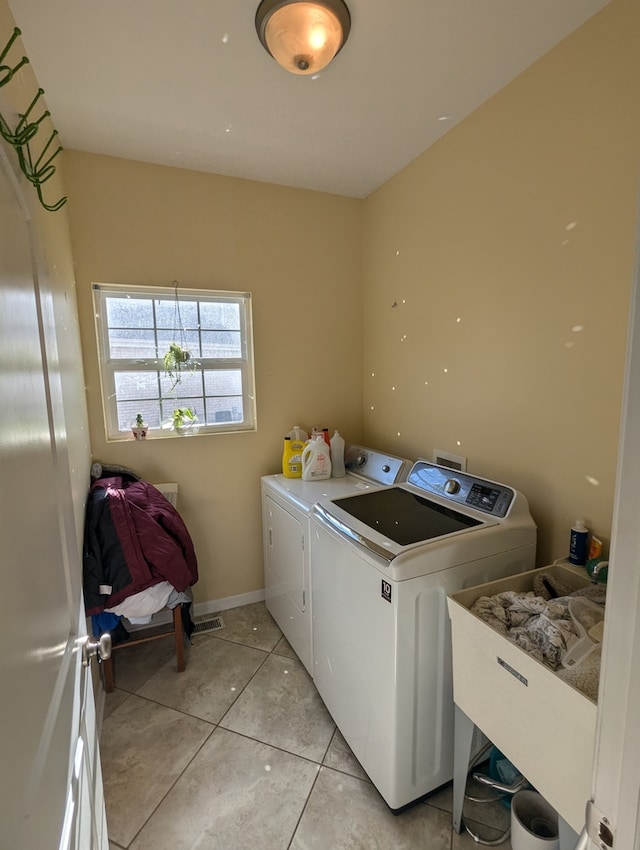 washroom with independent washer and dryer, light tile patterned floors, and sink