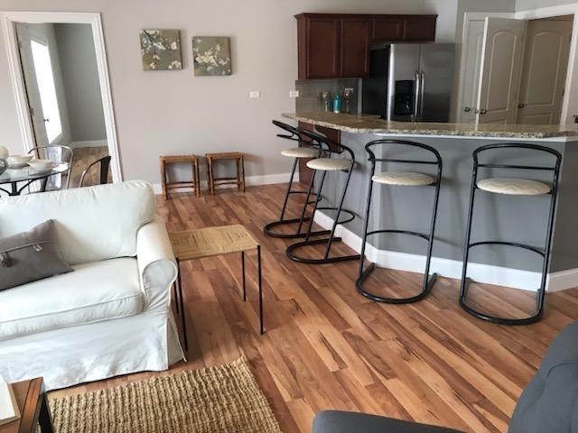 kitchen featuring decorative backsplash, light wood-style floors, stainless steel fridge, a breakfast bar area, and baseboards