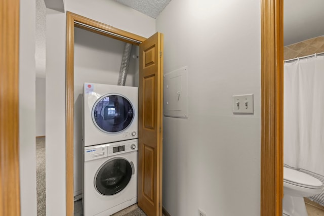 washroom featuring a textured ceiling and stacked washer and clothes dryer