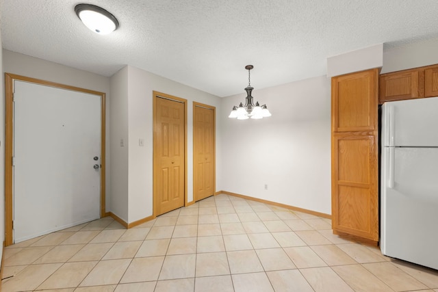 kitchen with white fridge, an inviting chandelier, a textured ceiling, and hanging light fixtures