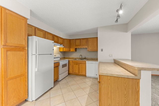 kitchen featuring sink, a textured ceiling, white appliances, a kitchen bar, and kitchen peninsula